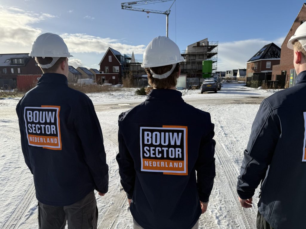 Vakmensen van Bouwsector Nederland met helm en bedrijfsjas kijken naar gevels van woningen in aanbouw